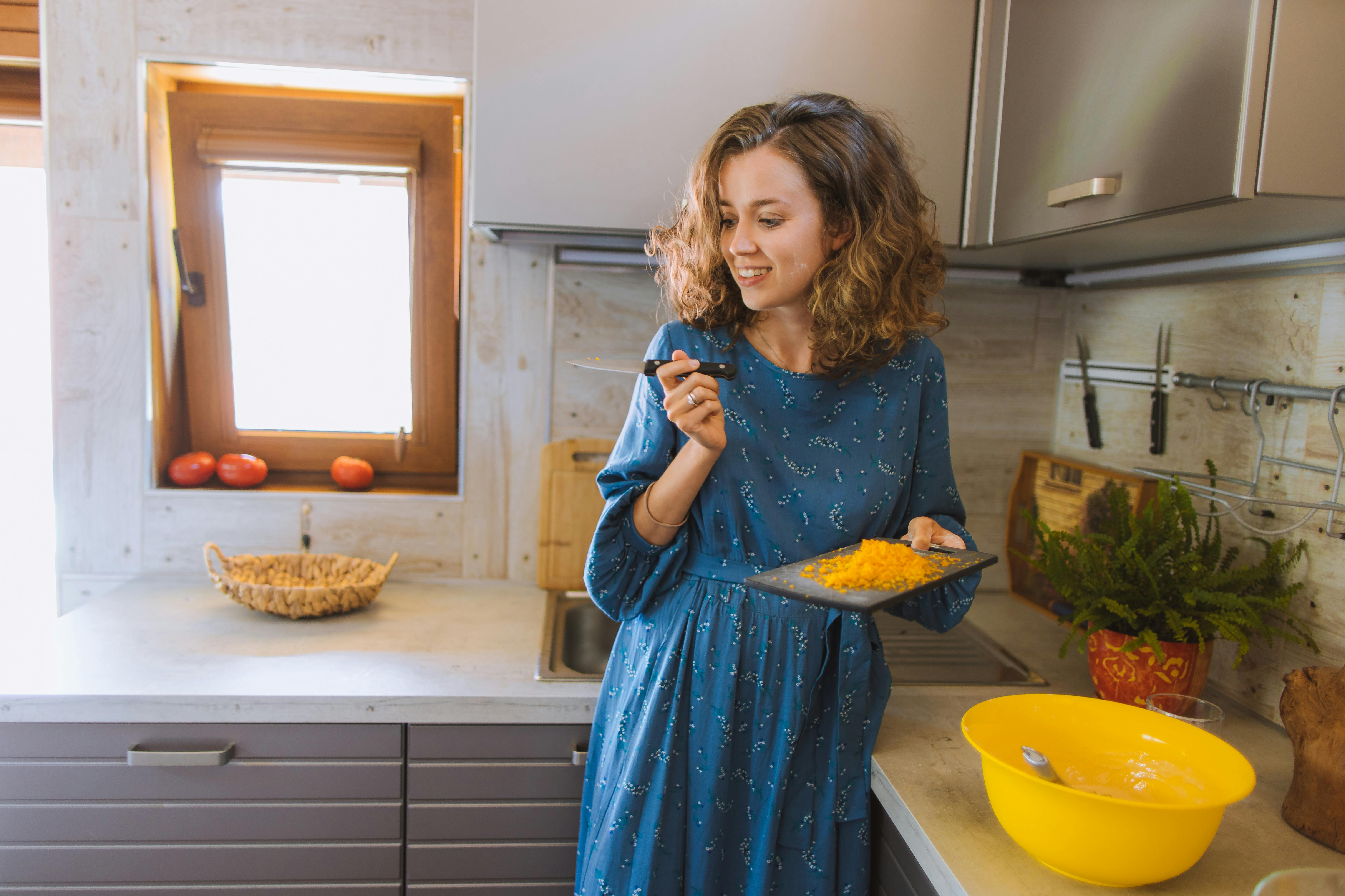 woman in blue long sleeve dress holding a knife and a cutting board