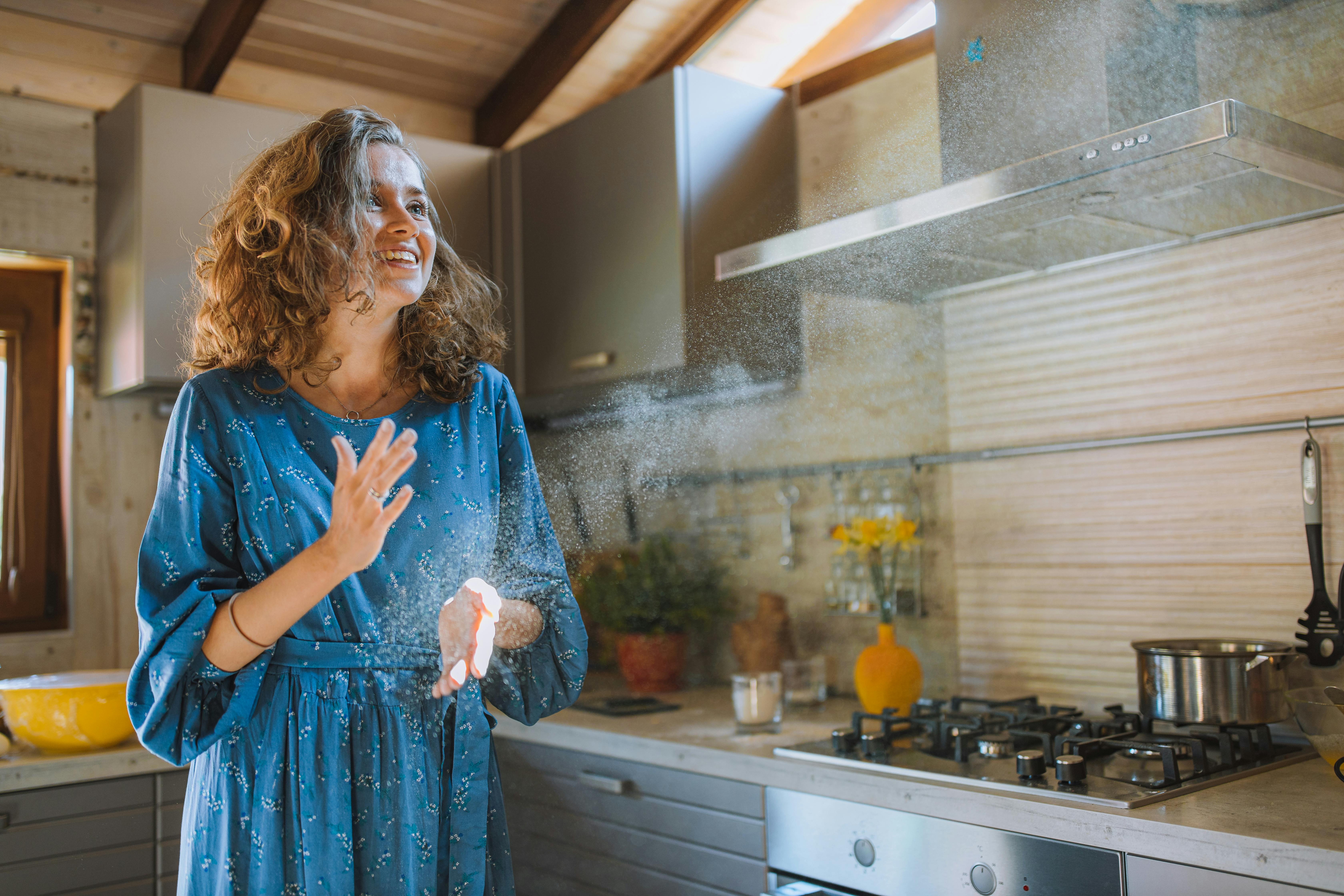 woman in blue dress standing in kitchen