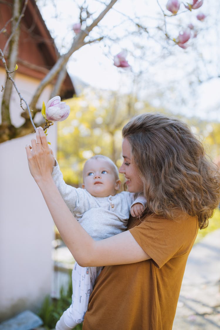 Woman With A Baby Reaching For A Flower