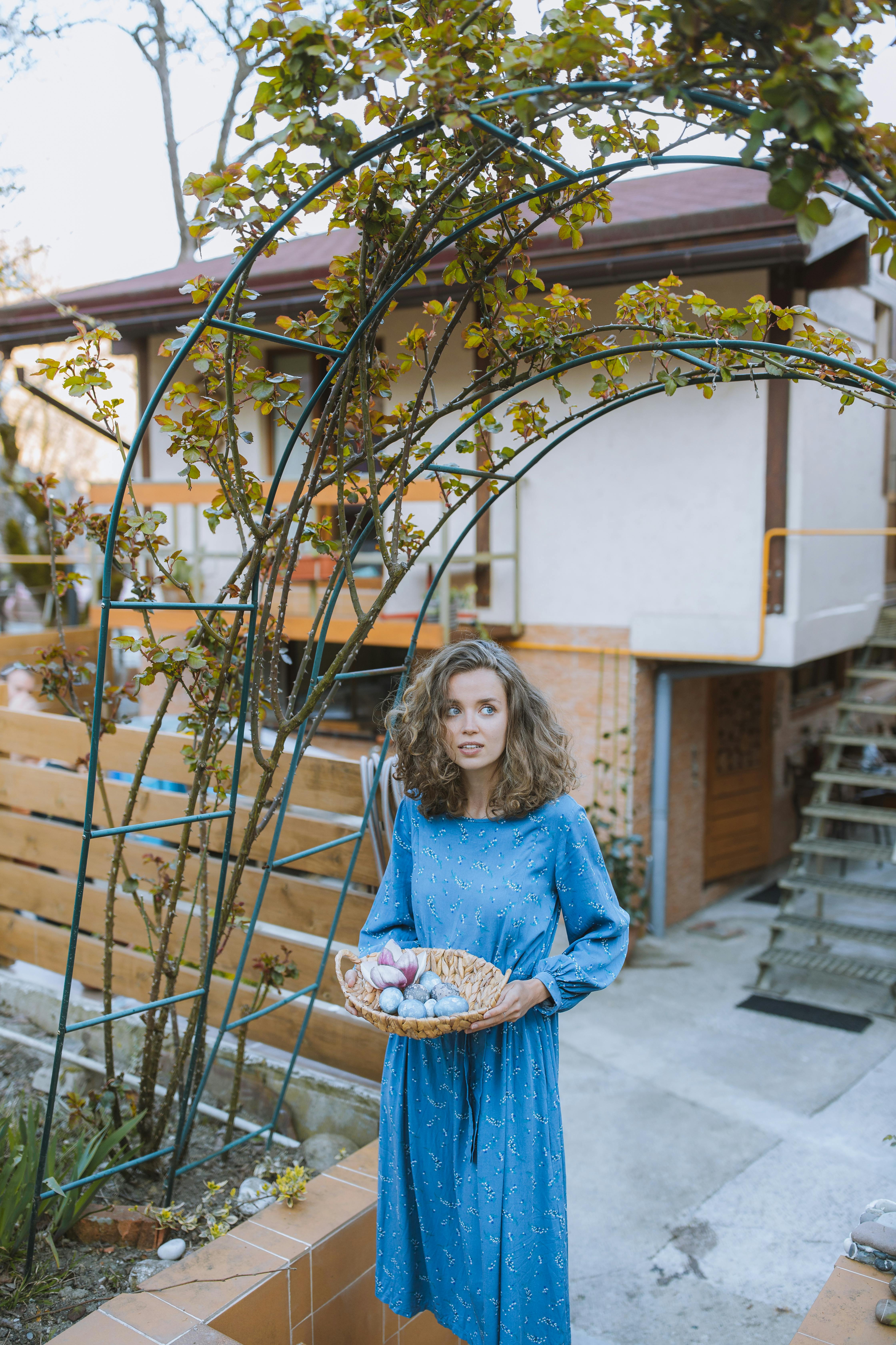 woman in blue long sleeve dress with eggs basket