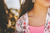 特写镜头中，一位戴着金耳环、头戴花卉的女子位于户外