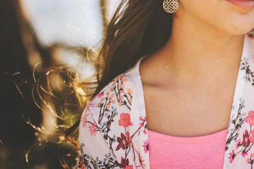 Free Close-up of a woman with gold earrings and floral top, outdoors. Stock Photo