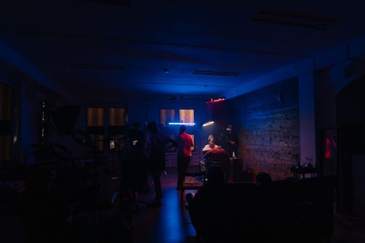 A dimly lit tattoo studio with artists working under neon lights, creating an immersive creative scene.