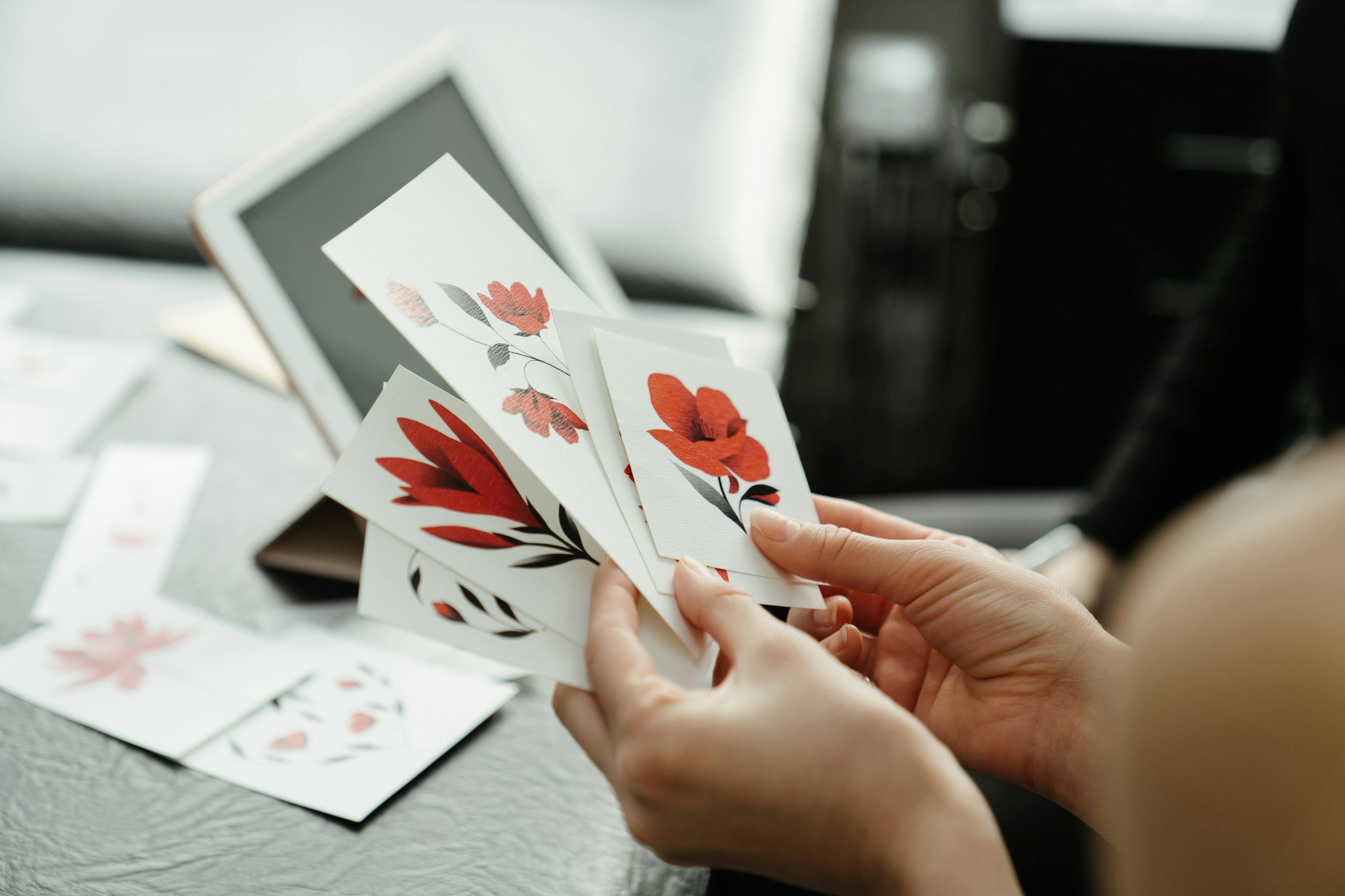 person holding white and red flower card