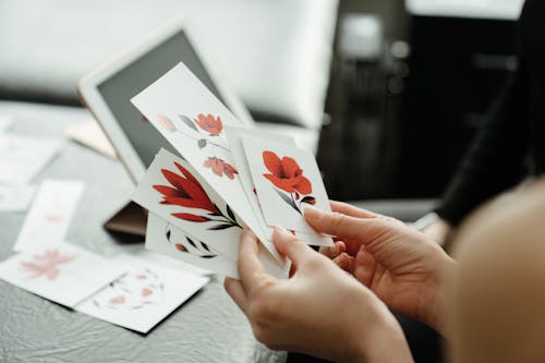 Person Holding White and Red Flower Card