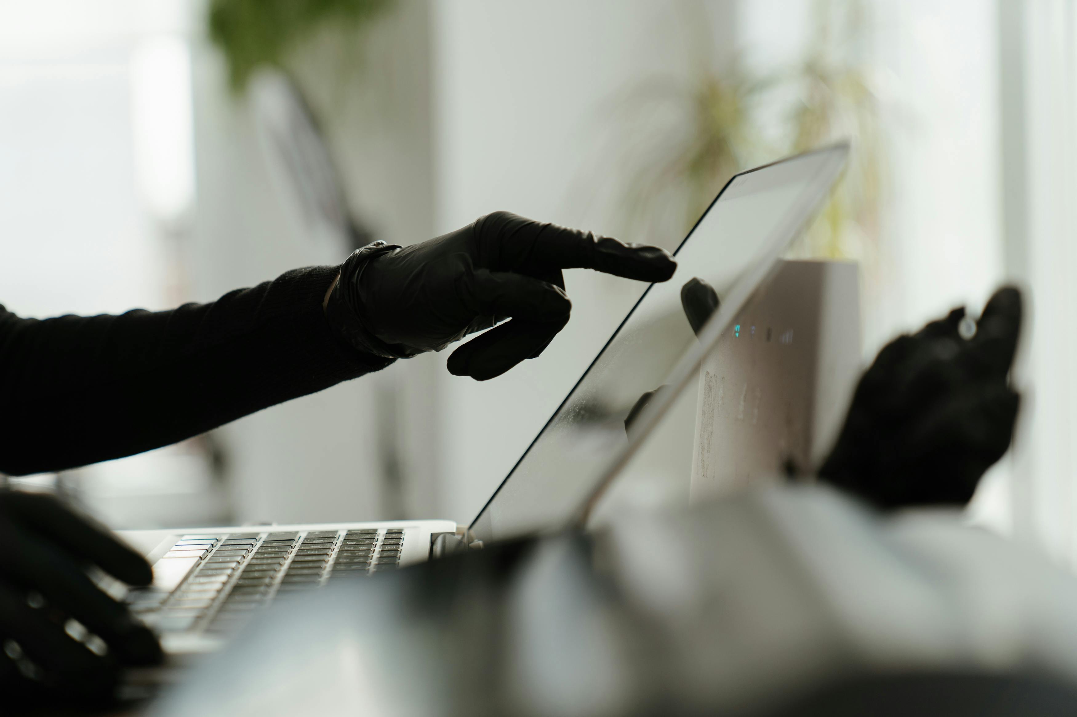 Close-up of a gloved hand interacting with a laptop in a sleek, modern office environment.