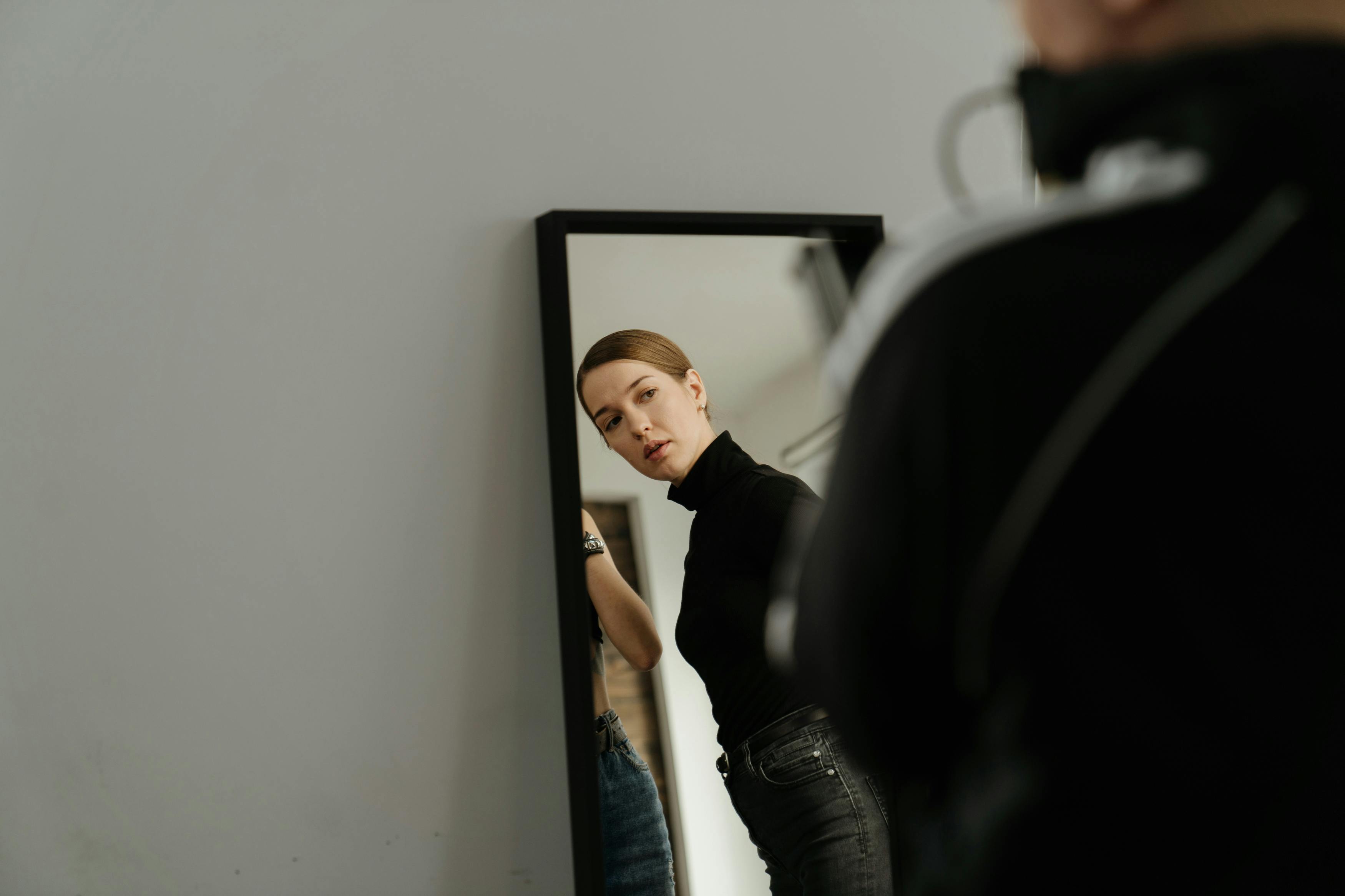 man in black t shirt and blue denim jeans standing in front of mirror