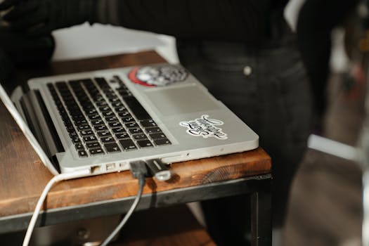 A close-up of a laptop with stickers on a wooden table situated in a home office setting.