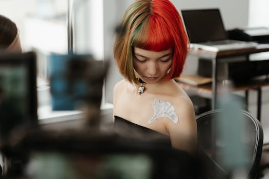 Asian woman with vibrant hair preparing for a tattoo session in a contemporary studio setting.