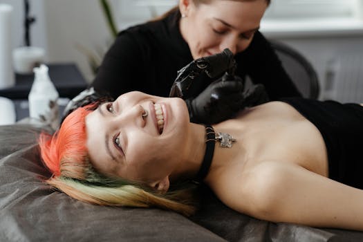 Smiling woman with colored hair getting a tattoo in a studio setting.