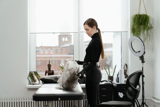 Tattoo artist in a sunlit studio setting up equipment near a large window.