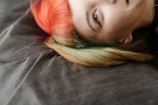 A captivating close-up showing a woman with striking multicolored hair lying on fabric.