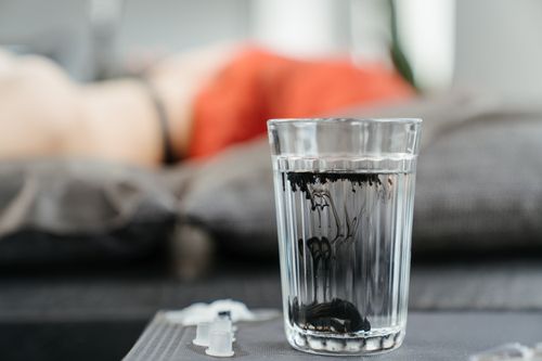 Free A detailed shot of black tattoo ink mixing with water in a glass at a tattoo studio. Stock Photo