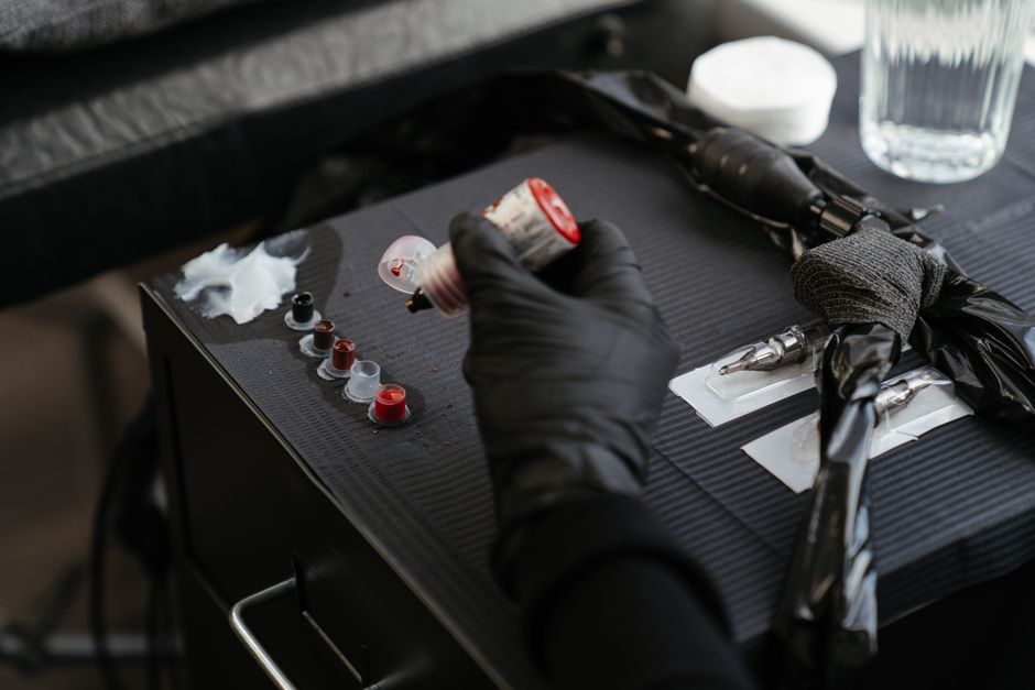 Tattoo mentor guiding an apprentice through safe setup in a professional studio Tattoo mentor guiding an apprentice through safe setup in a professional studio