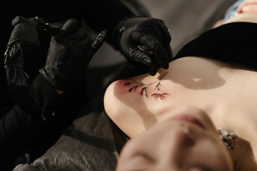 Free Close-up of a tattoo artist creating floral body art on a woman in a studio setting. Stock Photo
