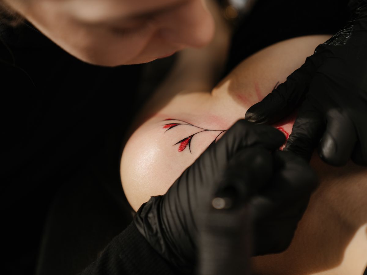 A small fine-line tattoo centred on a woman's upper back.