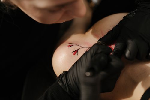 Free Close-up of a tattoo artist working on a floral design in a studio. Stock Photo