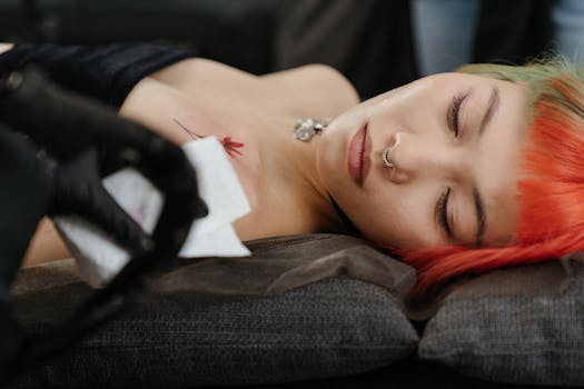 Close-up of an artistic tattoo process on a woman with colored hair in a studio setting.