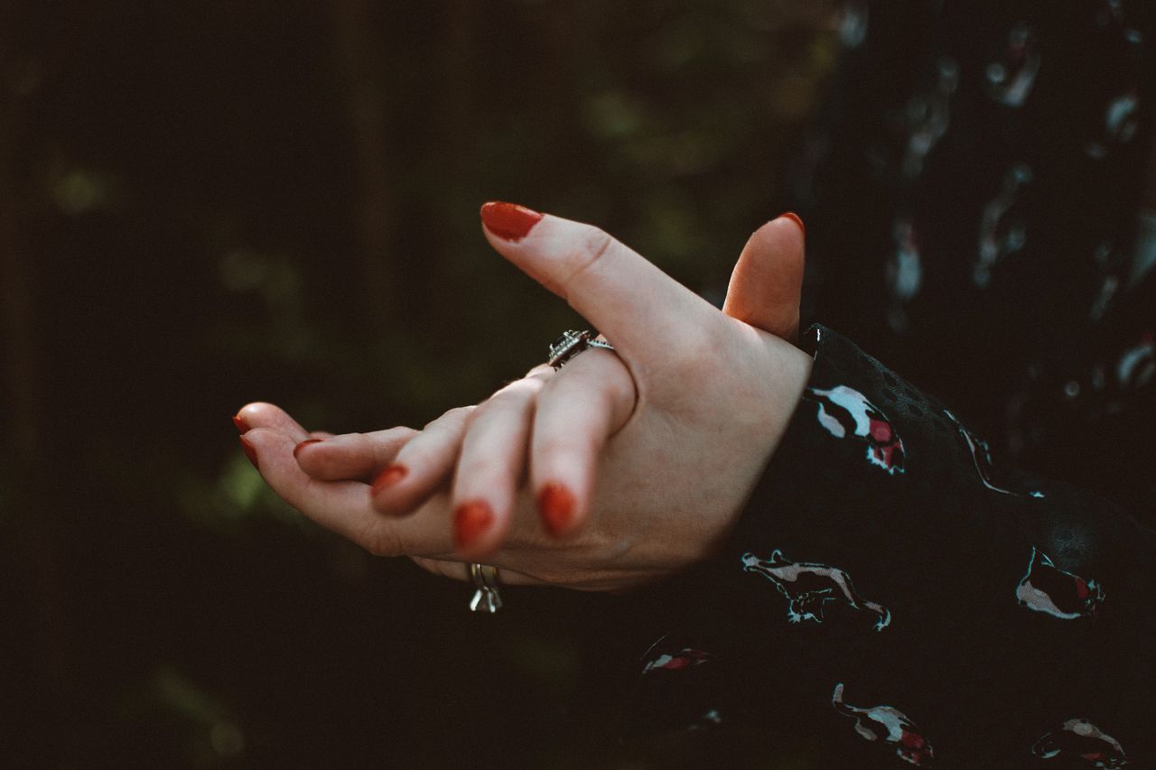 artistic close up of hands adorned with stylish rings and red nails em