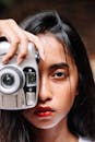 一位表情严肃的女子手持老式相机的艺术肖像，突出了摄影主题