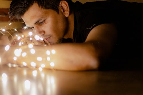 Close Up Photo of Man Looking at String Lights