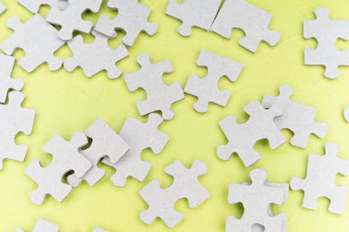 Close-Up Shot of Jigsaw Puzzle Pieces on a Yellow Surface