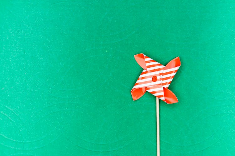 Close-Up Shot Of A Red Pinwheel On A Green Surface