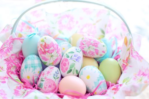 Brightly decorated Easter eggs in a floral basket, perfect for holiday celebration.