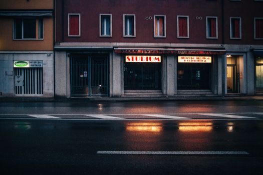 Moody urban night scene with illuminated storefronts in Padua, Italy.