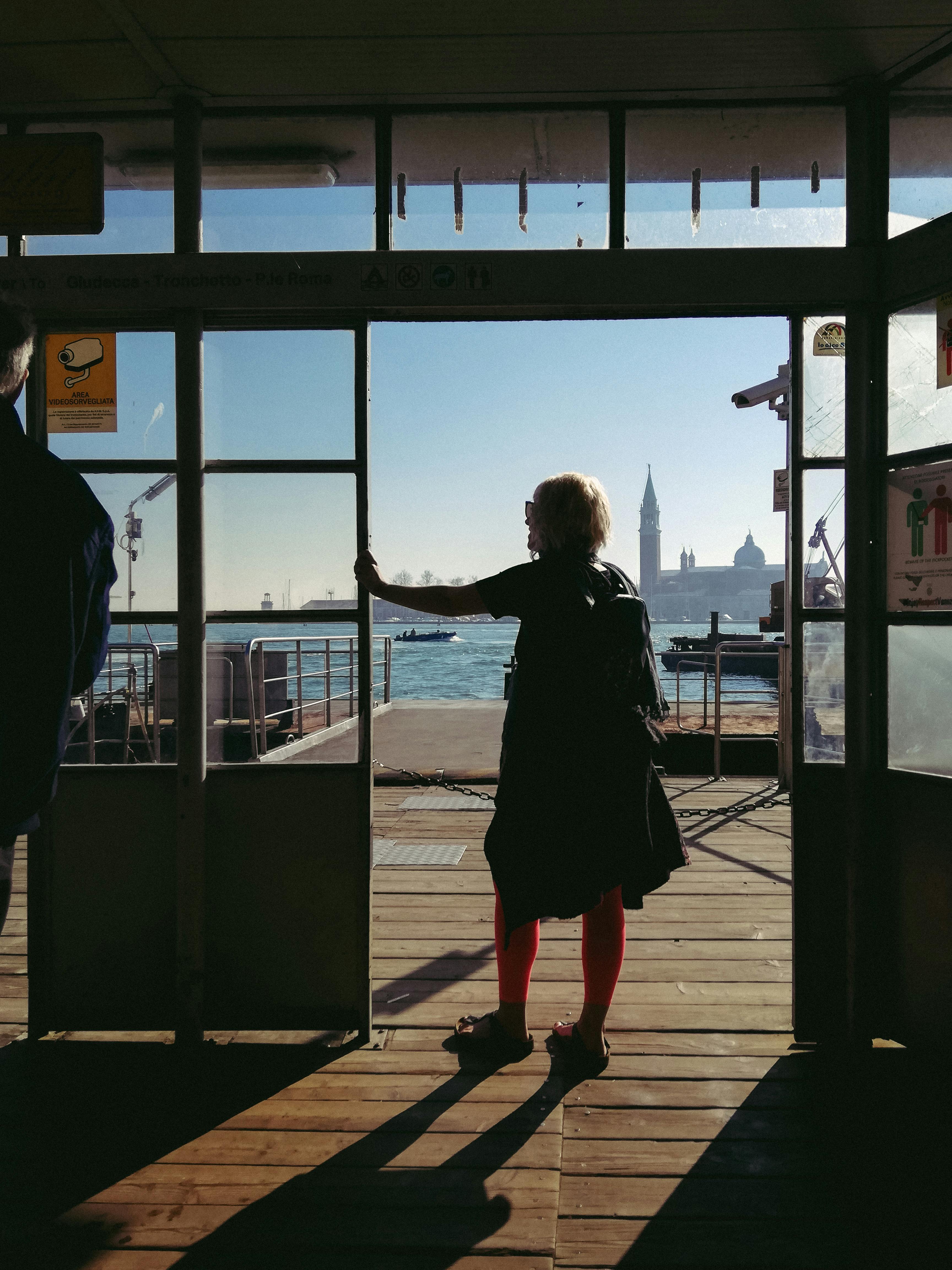 woman in black coat standing near glass window