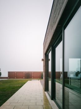 Contemporary building with glass panels reflecting the surroundings on a foggy day in Venice.