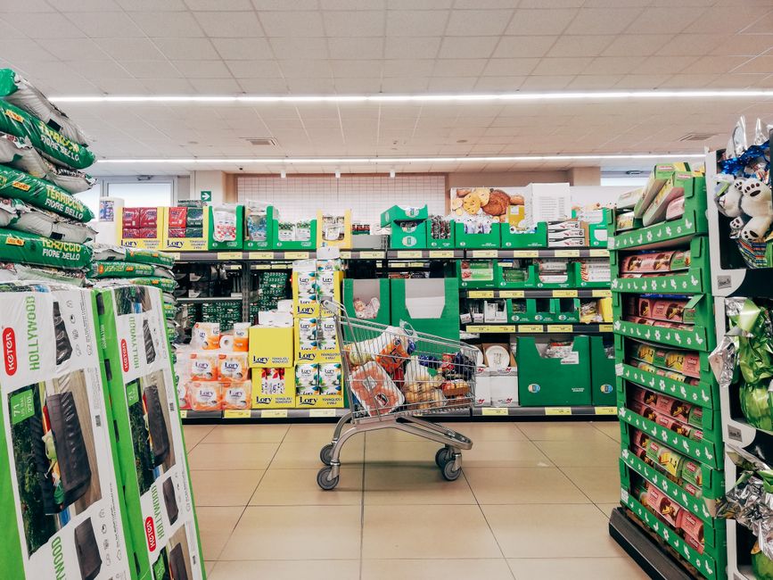 Shopper placing groceries into reusable shopping bags at a store checkout counter