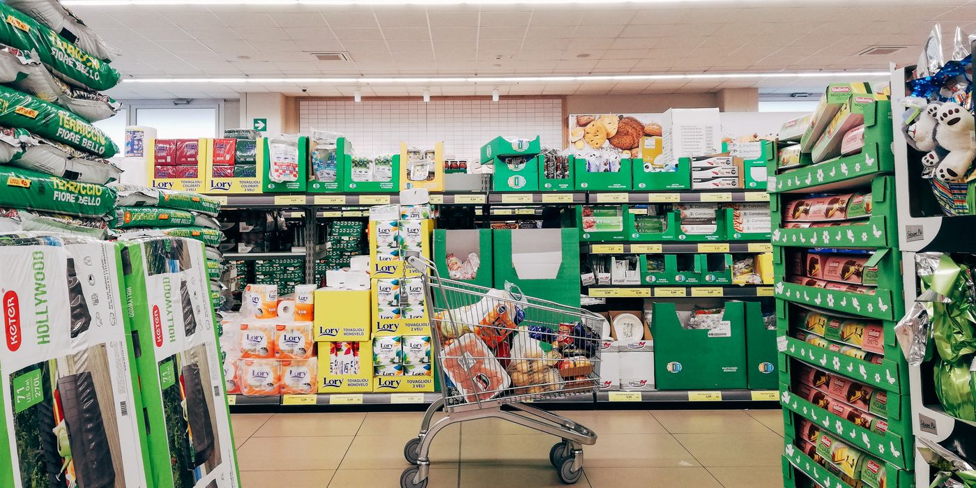 Shopping cart in a vibrant supermarket aisle in Padova, Italy.
