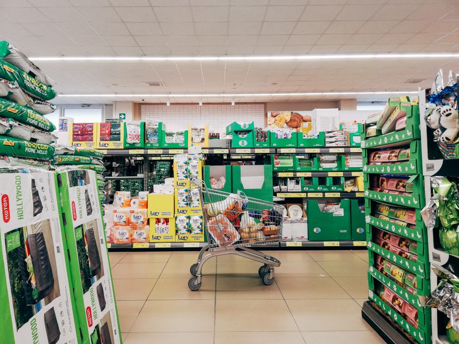 A shopping cart in a supermarket aisle, illustrating rising grocery costs