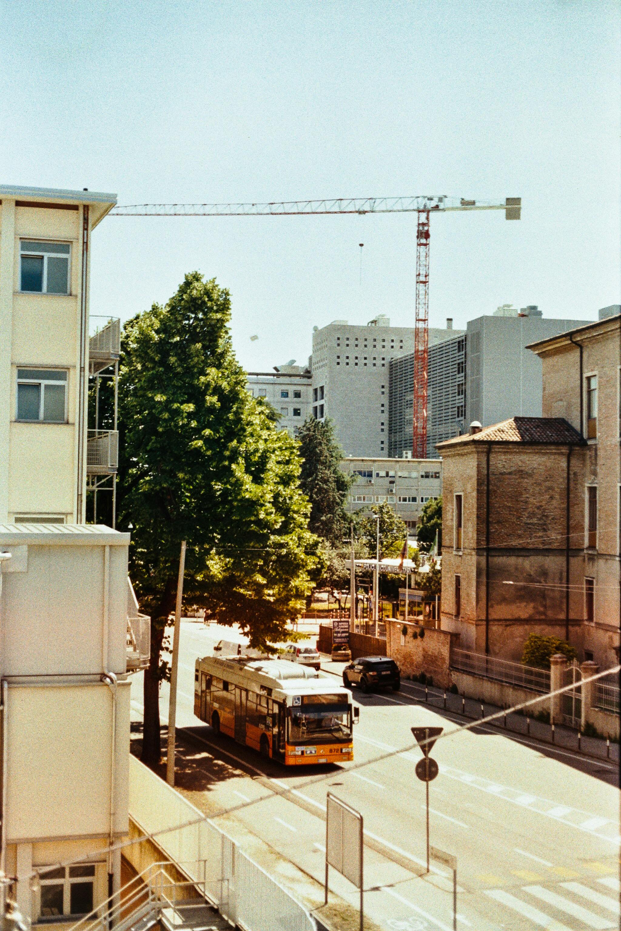 High angle shot of a trolley bus on a city street in Naples, Italy, with buildings and construction crane.