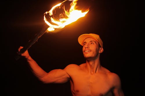 Topless Man Holding Stick with Fire