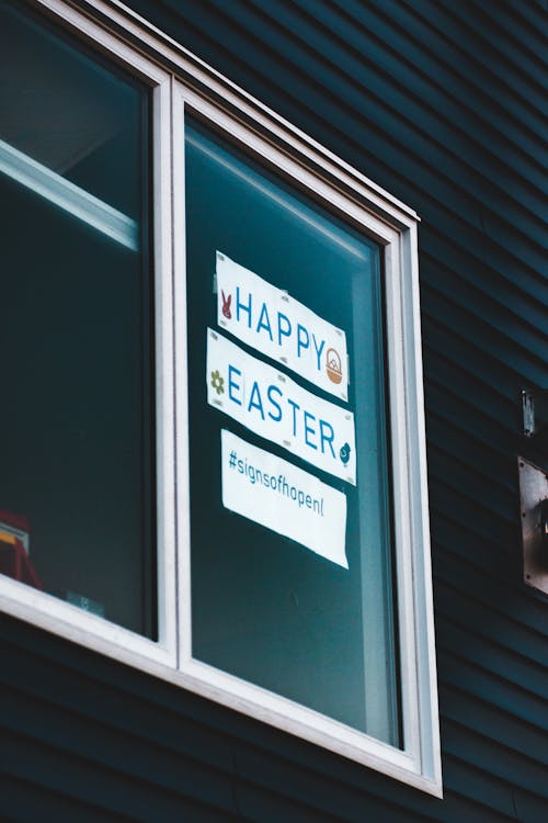 Outside of window with Happy Easter and hashtag lettering on white paper sticked on glass