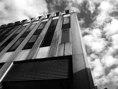 从低角度拍摄的现代建筑，呈现出戏剧性的云层和钢铁元素