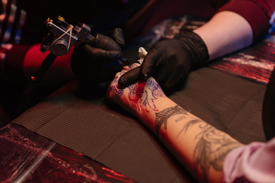Tattoo apprentice practicing steady line work under a mentor's supervision Tattoo apprentice practicing steady line work under a mentor's supervision