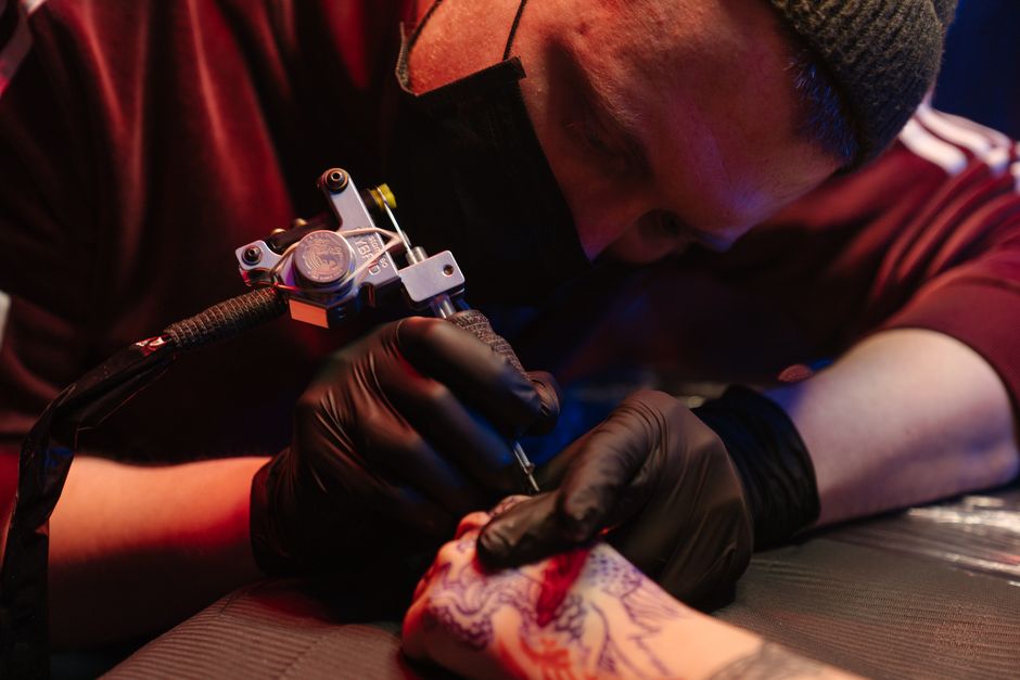 An apprentice learning to tattoo on fake skin under the supervision of a mentor at Ink Different Tattoos.