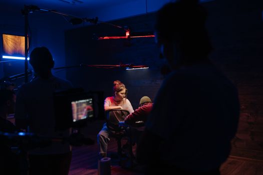 Indoors film set illuminated by neon lights, showcasing a camera crew in action.