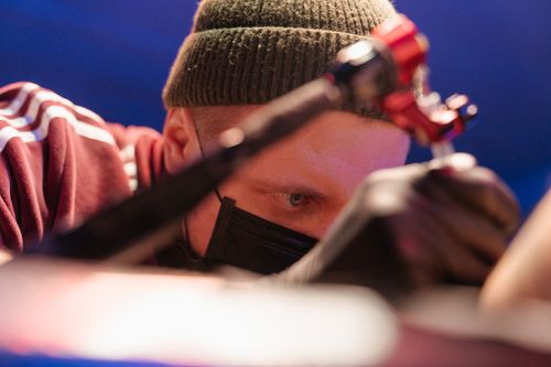 Free Close-up of a tattoo artist focused intently while working in a professional studio setting. Stock Photo