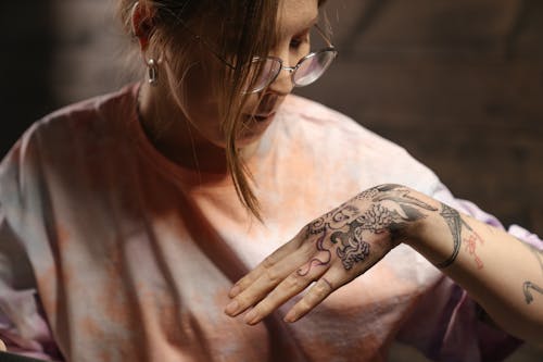 Woman in Orange Shirt With Tattoo on Her Left Hand