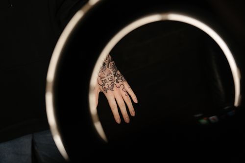 Free A tattooed hand illuminated by a ring light in an artistic studio environment. Stock Photo