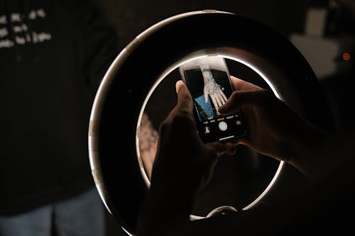 Person Holding Iphone 6 Taking Photo of Round Mirror