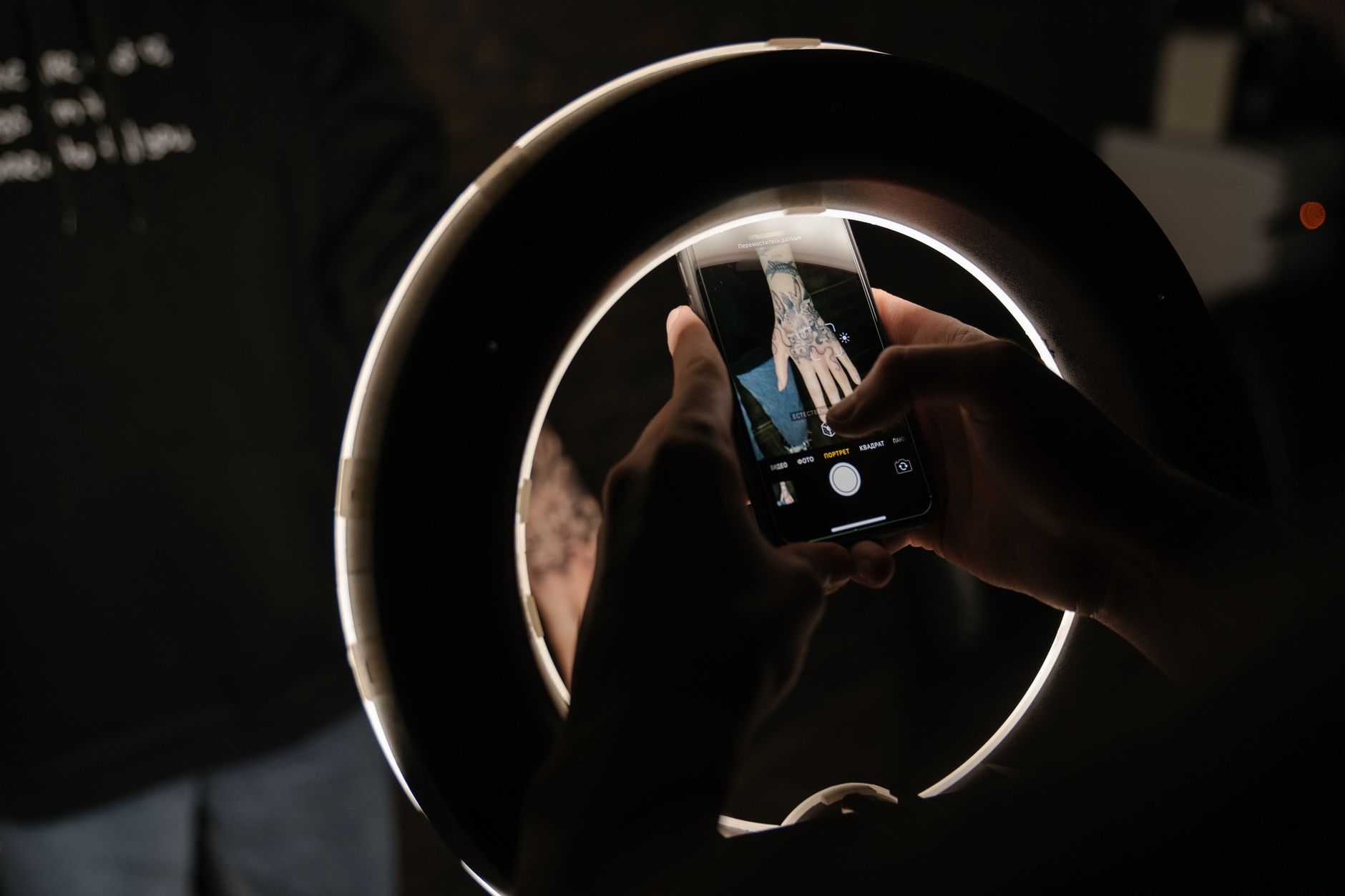 手機微距拍照技巧:對焦距離與補光實戰指南 A smartphone captures a hand tattoo under a ring light, highlighting tattoo artistry.