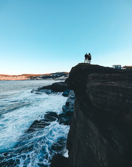 Photo Of People Standing On Cliff Edge