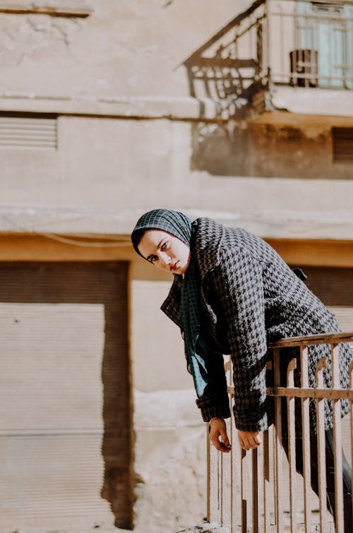 женщина в черно белом хиджабе стоит у коричневого деревянного забора