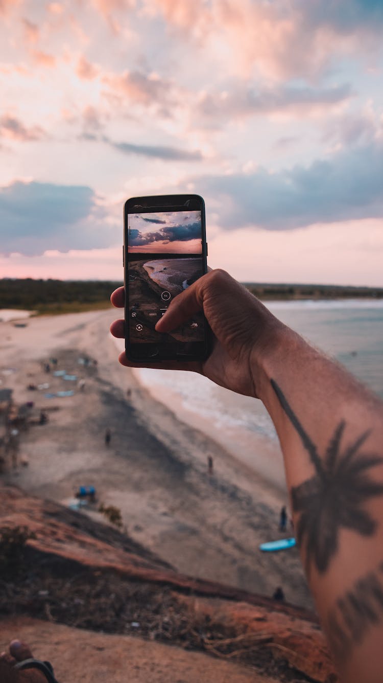 Person Holding Black Iphone 5 Taking Photo Of Beach