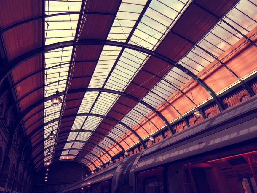 Interior view of a modern train station featuring a striking glass and steel arched roof.